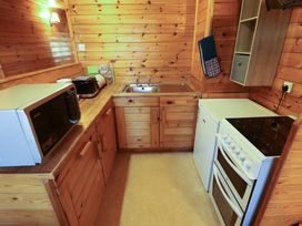 A small kitchen with wooden cabinets a microwave toaster bread bin sink stove and refrigerator at Kestrel in Withern near Alford