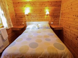A bedroom with a double bed with polka dot bedding and wooden walls at Kestrel in Withern near Alford