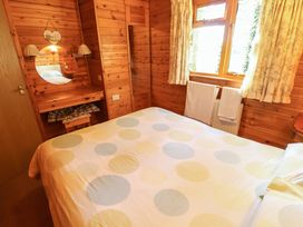 A bedroom with a bed a dressing table mirror and window with curtains at Kestrel Withern near Alford