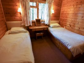 A bedroom with two single beds a small wooden desk with a mirror and a stool and floral curtains at Kestrel in Withern near Alford