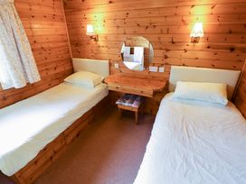 A bedroom with two single beds a wooden dressing table a round mirror and wall lights at Kestrel in Withern near Alford