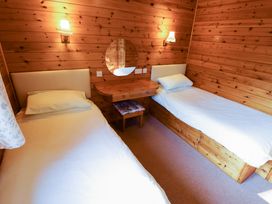 A small bedroom with two single beds a wooden dressing table with a round mirror and wooden walls at Kestrel in Withern near Alford