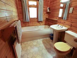A bathroom with wooden walls a bathtub a sink a toilet and a towel rack with a towel at Kestrel in Withern near Alford