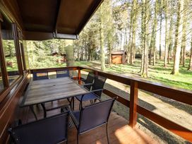 A wooden deck with a table and six chairs overlooking a wooded area at Kestrel in Withern near Alford