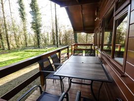 A wooden outdoor deck with a table and chairs overlooking a grassy area and trees at Kestrel in Withern near Alford