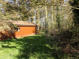 A wooden cabin next to a grassy area and trees at Kestrel in Withern near Alford