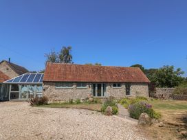 A stone building with a glass structure and garden at Dragon Cottage Musbury