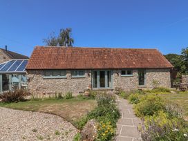 A stone building with a garden and pathway at Dragon Cottage in Musbury
