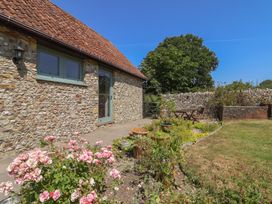 A garden with a stone wall and wooden table at Dragon Cottage in Musbury