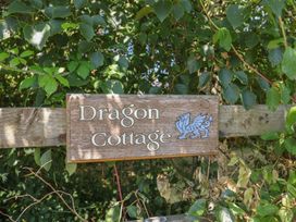 A wooden sign for Dragon Cottage with a dragon design in Musbury