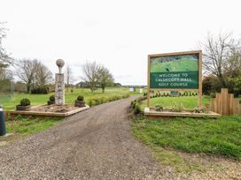 Entrance to Caldecott Hall golf course with a sign and golf ball sculpture near a gravel path