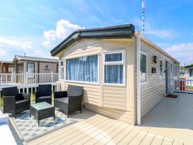 The exterior of a beige mobile home with a deck and black outdoor furniture at Oakley Retreat in Fritton near Belton