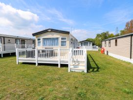 A mobile home with a white railing deck and chairs on grass at Oakley Retreat in Fritton near Belton