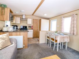 A kitchen with dining table and chairs next to a sofa at Oakley Retreat in Fritton near Belton