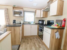 A kitchen with wooden cabinets a microwave a coffee machine and a stove at Oakley Retreat in Fritton near Belton