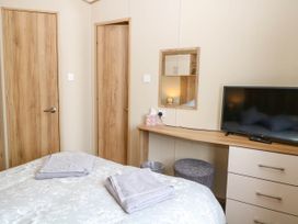A bedroom with a bed with towels on it a wooden desk with a television and a mirror on the wall oakley retreat fritton near belton