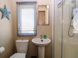 A bathroom with a toilet sink mirror window blinds shower and blue star decoration at Oakley Retreat in Fritton near Belton
