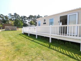 A mobile home with a white railing and grass lawn at Oakley Retreat in Fritton near Belton