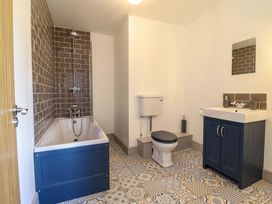 A bathroom with a bathtub, shower, toilet, and sink at The Farmhouse in Oswestry