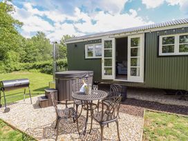 An outdoor space with a hot tub, table, chairs, and grill at Bluebell in Grimsby