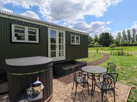 An outdoor area with a hut, hot tub, table, and chairs at Bluebell in Grimsby