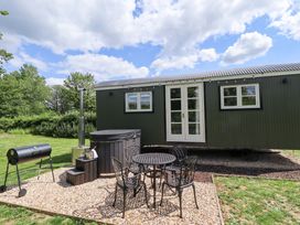 An outdoor area with a house, table, chairs, grill, and hot tub at Bluebell in Grimsby