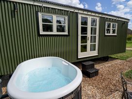 A hot tub beside a green cabin with windows and a door at Primrose in Grimsby