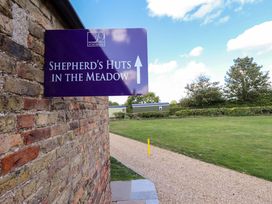 A sign for Shepherd's Huts in the Meadow with a pathway at Magnolia in Grimsby