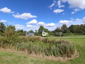Three green huts in a field with trees and blue sky at Snowdrop in Grimsby