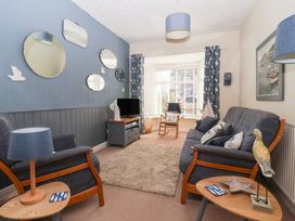 A living room with blue chairs a sofa mirrors on the wall and a TV at 48 Waxholme Road Withernsea