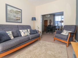 A living room with blue sofas a floor lamp and a painting on the wall at 48 Waxholme Road in Withernsea