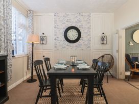 A dining room with a black table set for six with chairs and a floor lamp by patterned curtains at 48 Waxholme Road in Withernsea