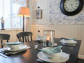A dining table set for four with bowls napkins and a candle in a glass holder near a window with blinds and a floor lamp at 48 Waxholme Road in Withernsea
