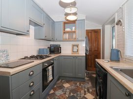 A kitchen with blue cabinets a gas stove an oven a microwave a kettle and a patterned tiled floor at 48 Waxholme Road in Withernsea