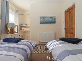 A bedroom with two single beds a dresser with a lamp a wooden door and a painting on the wall at 48 Waxholme Road Withernsea