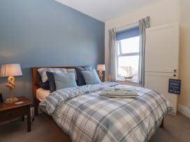 A bedroom with a double bed, bedside table with lamp, window with curtains, and a cupboard at 48 Waxholme Road in Withernsea