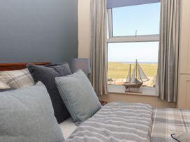 A bedroom with a bed pillows a lamp and a window showing a sailboat model and grassland outside at 48 Waxholme Road in Withernsea