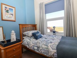 A bedroom with a wooden bed and nightstand with a lighthouse decoration and framed picture on a blue wall at 48 Waxholme Road in Withernsea