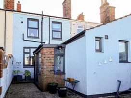 The back of a light blue brick house with multiple windows potted plants and small table with flower pots at 48 Waxholme Road in Withernsea
