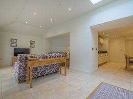 A living room with a sofa, TV, dining table, and kitchen area at The School in Mungrisdale near Caldbeck