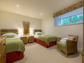 A bedroom with two beds and a chair at The School in Mungrisdale near Caldbeck