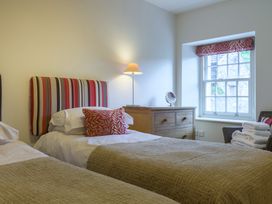 A bedroom with two beds, a lamp, and a window at The School in Mungrisdale near Caldbeck