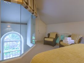 A bedroom with a bed and two chairs at The School in Mungrisdale near Caldbeck