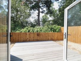A wooden deck area surrounded by trees at Barn Owl Lodge