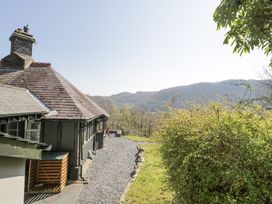 A gravel path beside a house with a slate roof and a green bush with hills in the background at Bwthyn y Coediwr in Tan Y Bwlch Maentwrog
