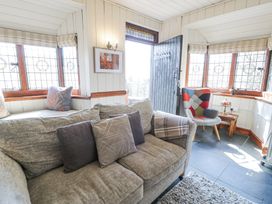 A sitting room with a gray sofa and colorful armchair by leaded windows at Bwthyn y Coediwr The Woodcutters Cottage in Tan Y Bwlch Maentwrog