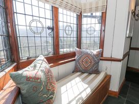 A window seat with striped cushion and patterned pillows at Bwthyn y Coediwr The Woodcutters Cottage in Tan Y Bwlch Maentwrog