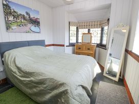 A bedroom with a bed a dresser with mirror and a standing mirror near windows at Bwthyn y Coediwr The Woodcutters Cottage in Tan Y Bwlch Maentwrog