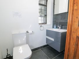 A bathroom with a toilet paper holder a sink cabinet and a window at Bwthyn y Coediwr The Woodcutters Cottage in Tan Y Bwlch Maentwrog