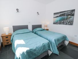A bedroom with two single beds with teal bedspreads two wooden bedside tables with lamps and a three-panel wall picture at Bwthyn y Coediwr (The Woodcutters Cottage) in Tan Y Bwlch Maentwrog